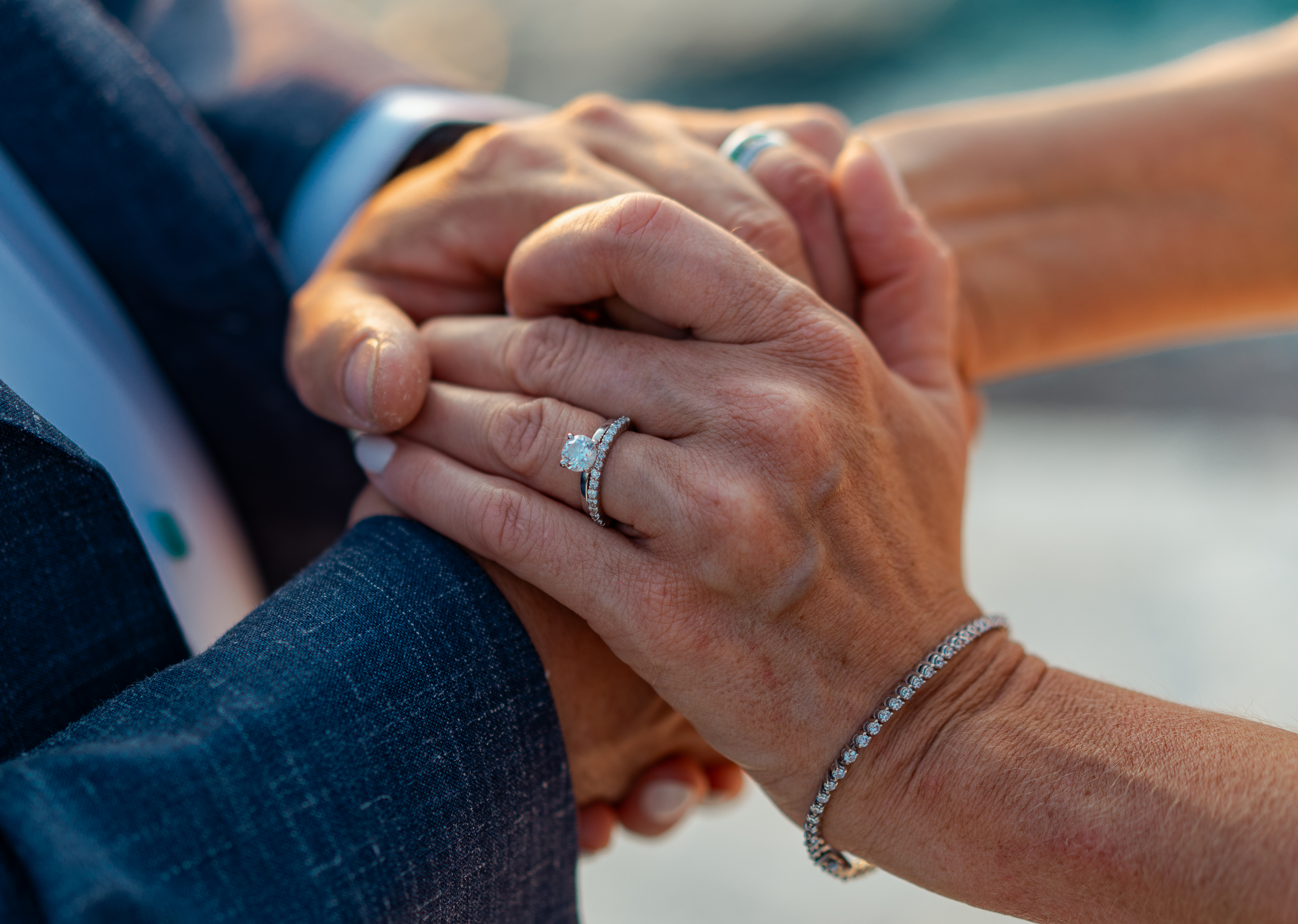 Joe and Sarah's hands clasped, Sarah's diamond ring in focus