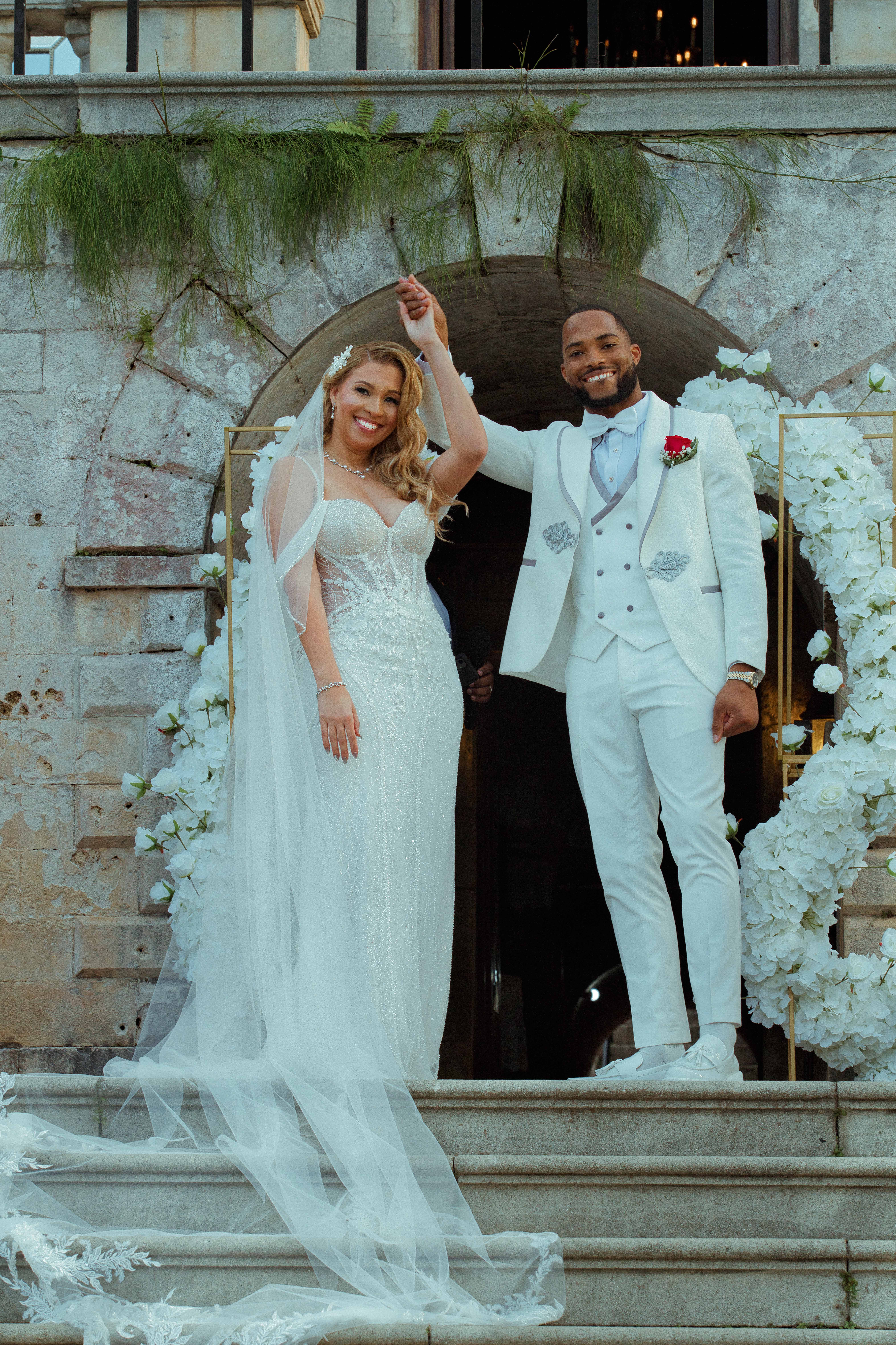 Debra and Nick celebrating on the stone steps under their floral arch